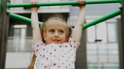 Young Girl Climbs Playground Monkey Bars in Urban Setting During Afternoon