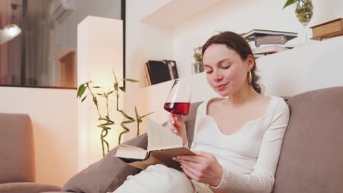 Woman Reading Book and Drinking Wine Indoors