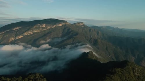Aerial view of mountain range and clouds of fog above the forest, wet morning weather, misty landsca