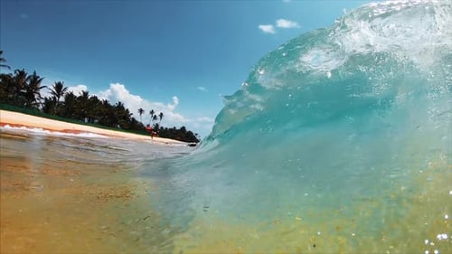 Ocean wave breaks over the sandy tropical beach