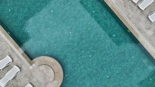 Aerial Video of Hotel Pool with Clear Blue Water Aqua Slide and Deck Chairs Around