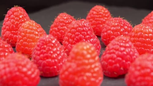 Ripe whole raspberries rotate as a backdrop for a promotional video. Juicy raspberry berry close