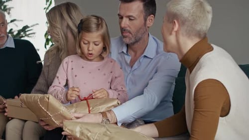 Family Exchanging Gifts and Talking on Couch