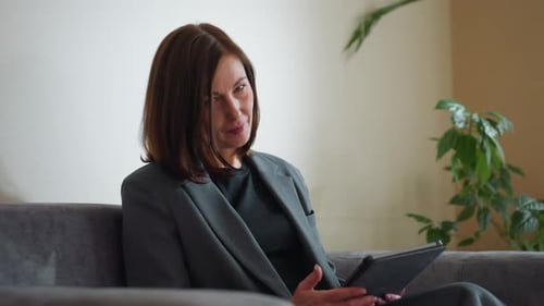 Businesswoman Browsing Tablet in Modern Office Lounge with Indoor Plants