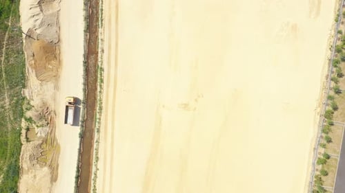 Dumper truck with sand is going, passing over highway construction side. Aerial View
