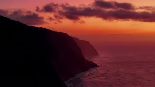 Lighthouse shines brightly over ocean as sunset paints the sky