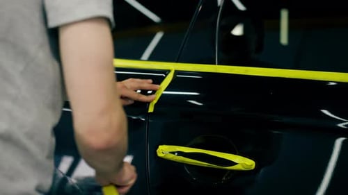Fahrzeugdetails an einer Tankstelle Ein schwarzer Autotechniker bedeckt Teile des Autos mit gelbem Klebeband