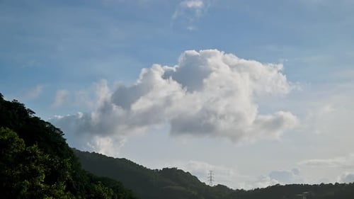 Über dem Gipfel des Berges befindet sich eine sich langsam bewegende weiße Wolke.