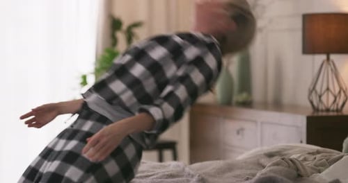 Woman Falling Backwards onto Comfortable Bed in Bedroom