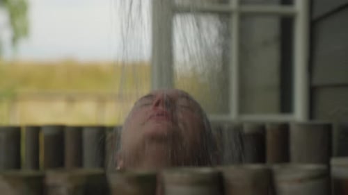 Refreshing outdoor shower bliss, close-up. Perfect for relaxation or spa scenes. Woman relaxing taki