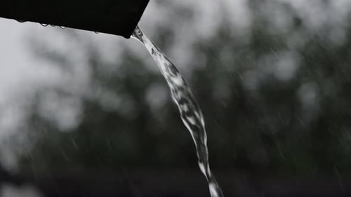 Un jet d'eau s'écoule du bord du toit pendant la pluie au Ralenti