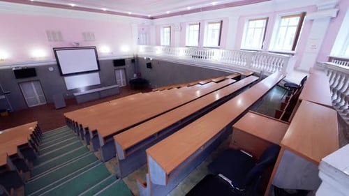 Gran sala de conferencias sin nadie. Auditorio vacío con una gran pizarra blanca y filas de escritorios.