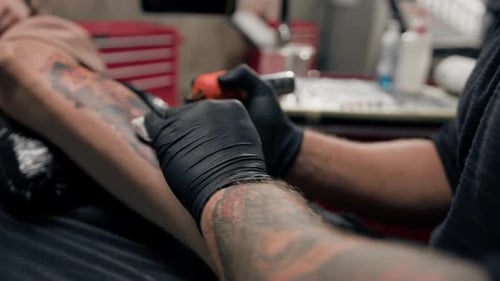 Close-up - the process of tattooing a woman on her leg. Male tattoo artist making a tattoo