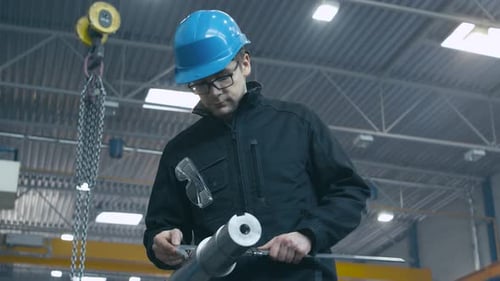 Der Fabrikarbeiter führt eine Qualitätskontrolle eines Metalldetails mit einem Messwerkzeug durch.