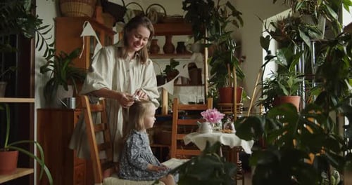 Woman Tying Ribbon in Young Girl's Hair at Home