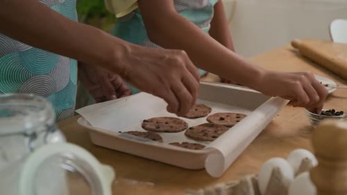 Vor dem Backen Schokoladentropfen zu den Keksen im Blech geben