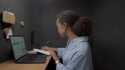 Woman Plans Using Laptop Calendar in Modern Office Booth