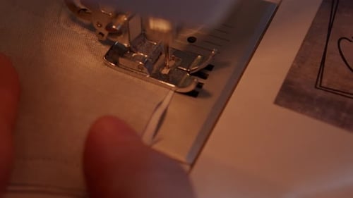 Close up of sewing machine foot sewing to the edge and operator releasing the needle