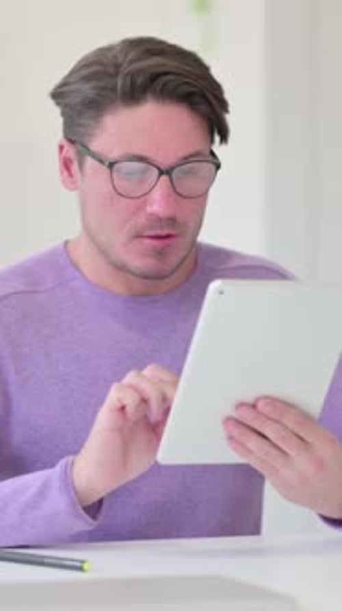 Man Using Tablet Receives Good News, Celebrates with Fist