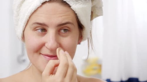 Woman Applying Makeup With Cosmetic Sponge in Bathroom