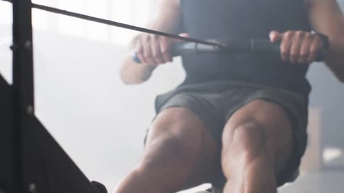 Using rowing machine, man exercising in gym, focusing on fitness and strength