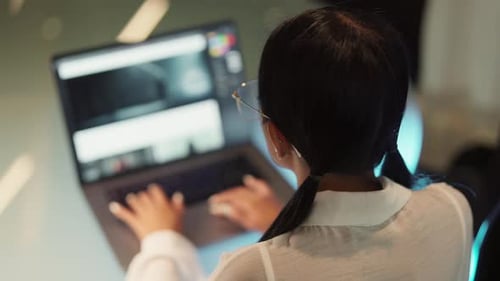 Vista posterior de una mujer que trabaja en el escritorio con su portátil