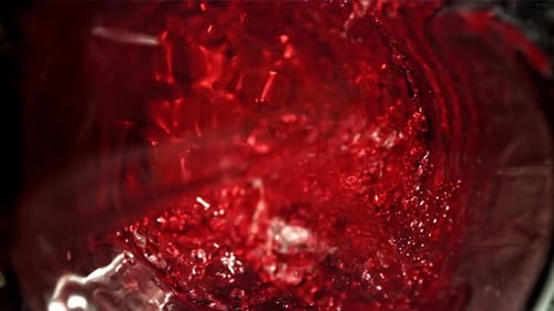 Rotwein wird in ein Glas gegossen. Ansicht, gefilmt mit einer Hochgeschwindigkeitskamera mit 1000 Bildern pro Sekunde