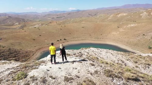 Aerial View Of Man And Woman Watching The Lake From The Hill