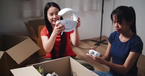Two young Asian women are opening boxes of belongings moved from old house.