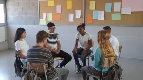 Group of Multiethnic Students Sitting in a Circle in a Classroom While Talking About Their Emotions