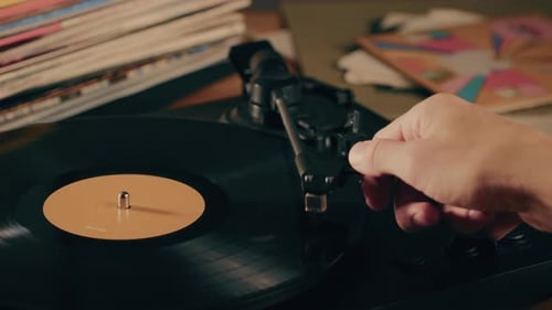 Hand placing needle on vintage vinyl record player