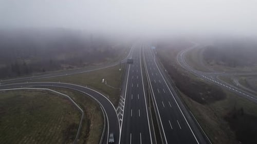 Aerial tilt down of cloudscape over rural highway with traffic during misty day