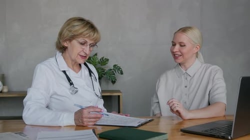 a Doctor and a Patient are Sitting at Tables in a Medical Office
