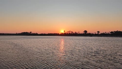 A beautiful sunset silhouetted against a swamp, river, and trees. This video is perfect for an