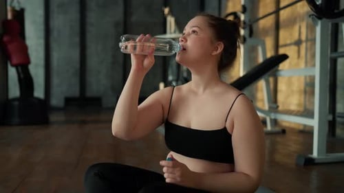 Woman Drinking Water After Workout at Gym