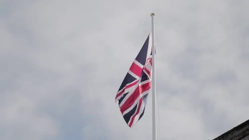 Union Jack Flag Waving Against Cloudy Sky