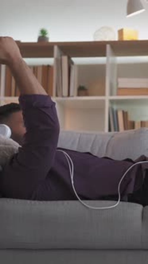 Young Adult with Headphones Relaxing on Couch