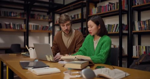 A Guy and His Female Colleague Come to a Common Decision While Studying with Books at a Table in the