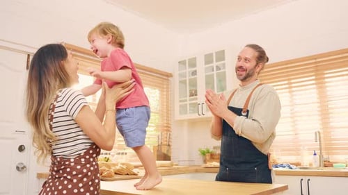 Parents Playfully Lifting Child in Kitchen