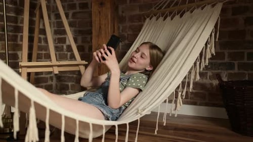 Girl Relaxing in Hammock with Mobile Phone