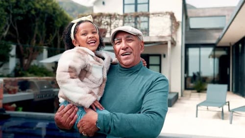 Grandfather Holding Granddaughter and Laughing Outside Home