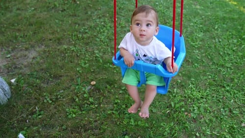 Cute Infant Swinging on Green Lawn