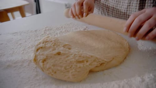 Young Female rolling out dough for a cake in the kitchen at home. Homemade pastry close up