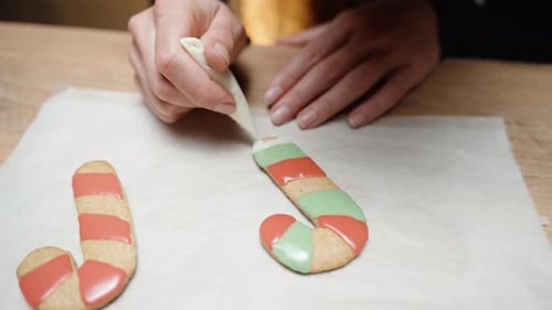 Creating a homemade Christmas gingerbread candy cane, the woman is filling it with multicolored