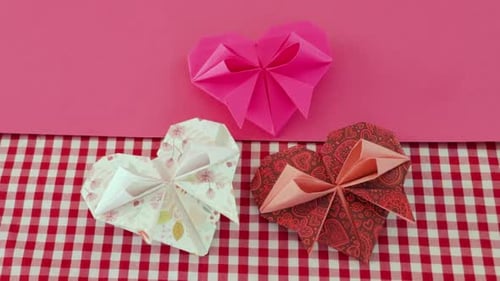 Three Origami Hearts on Pink and Checkered Background