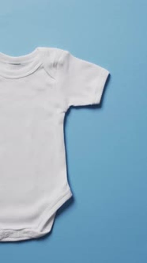 Vertical video of white baby grow with copy space on blue background