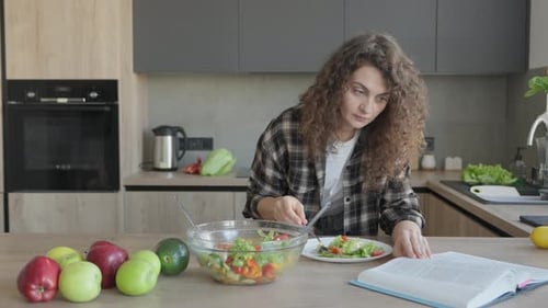 Young Woman Enjoys Salad While Reading in Kitchen