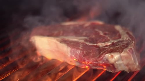 Raw Steak Cooking on a Grill with Flames