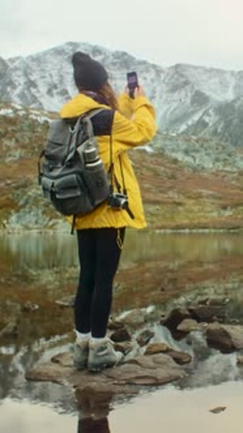 Photographer Standing on Rocks By Mountain Lake Enjoying Landscape