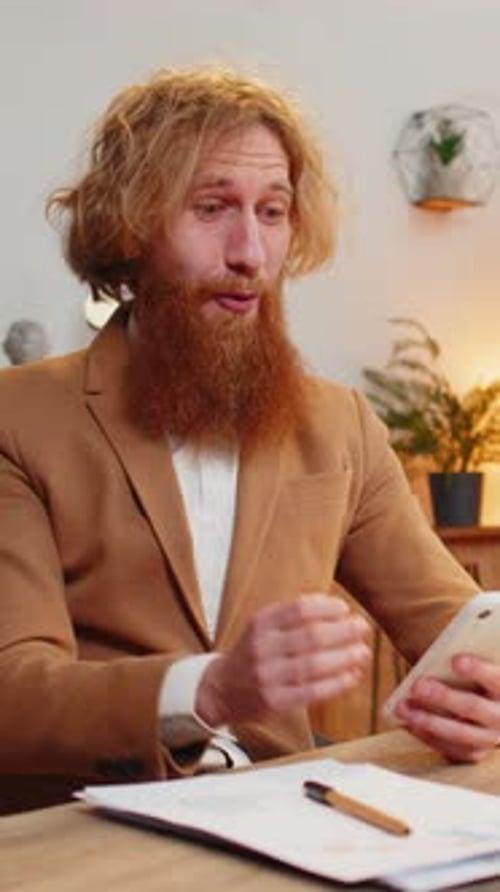 Man at Desk Reacts with Joy to Phone News